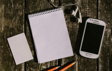 Kaboompics White smartphone with earphones and a notepad