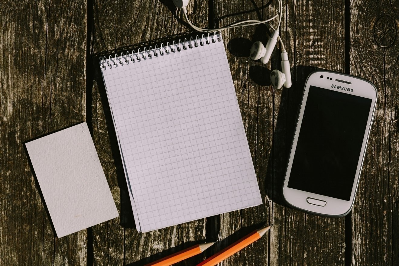 Kaboompics White smartphone with earphones and a notepad